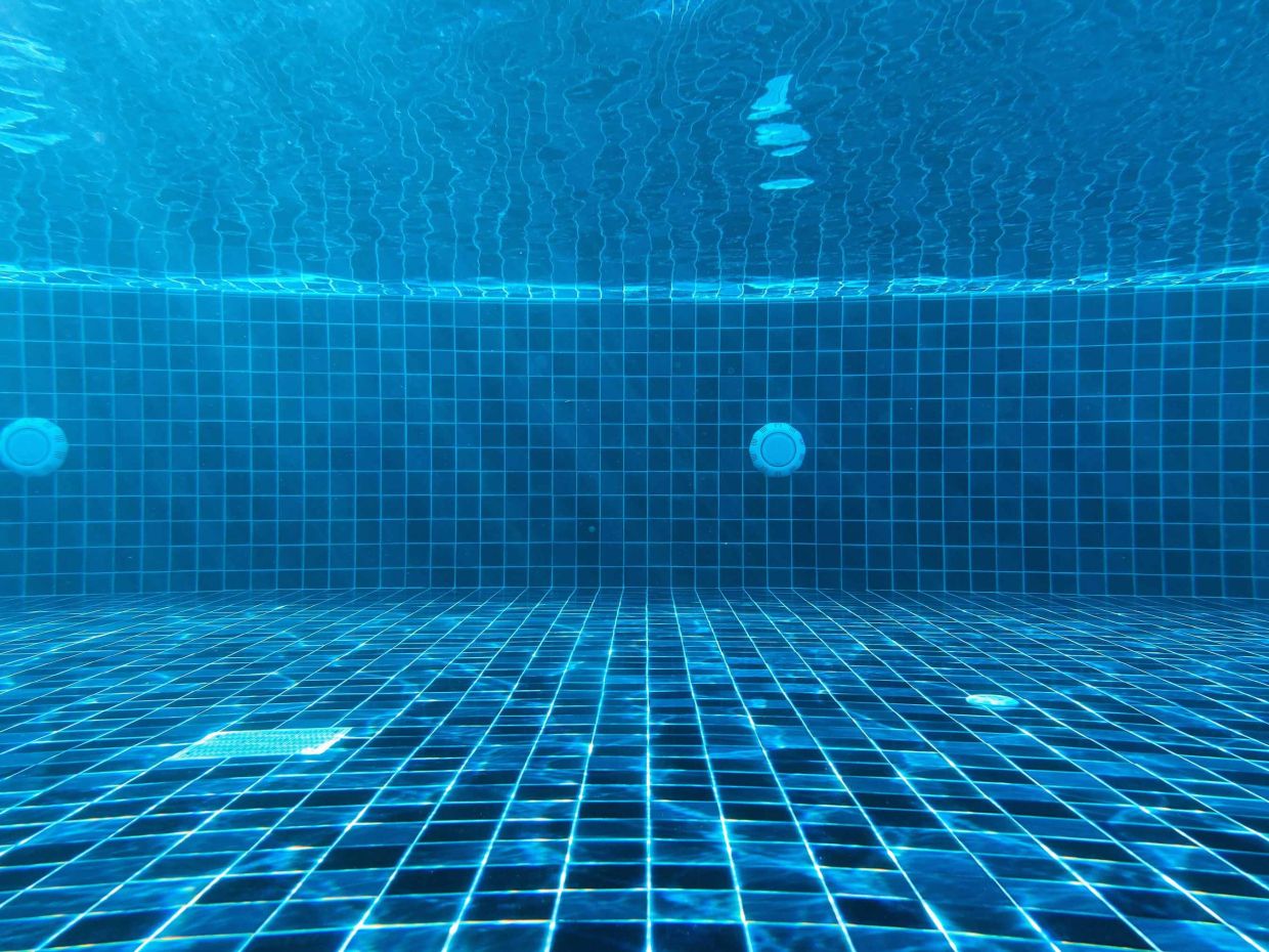 Piscine propre et claire avec mosaïque bleue sous l’eau, mettant en avant un service de gestion et d’entretien des piscines à Genève par Alfredo Services.