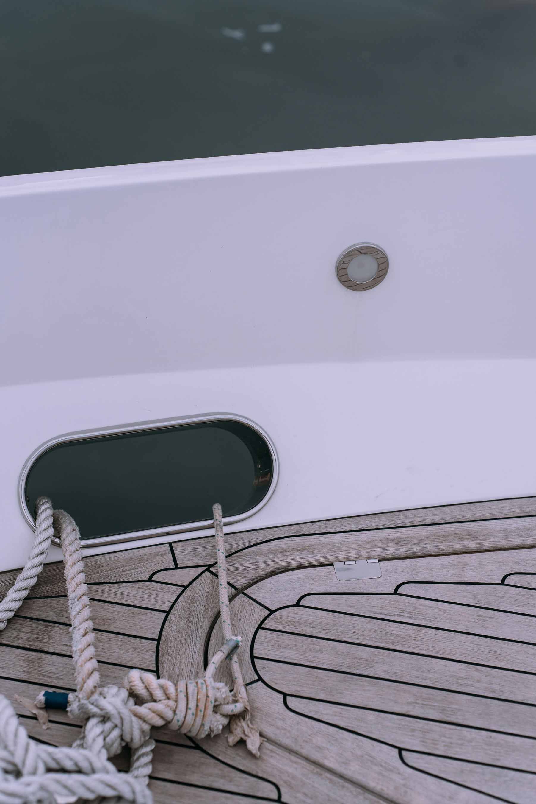 Pont en bois d’un yacht avec cordages et hublot, mettant en avant un service de nettoyage et detailing de bateaux à Genève par Alfredo Services